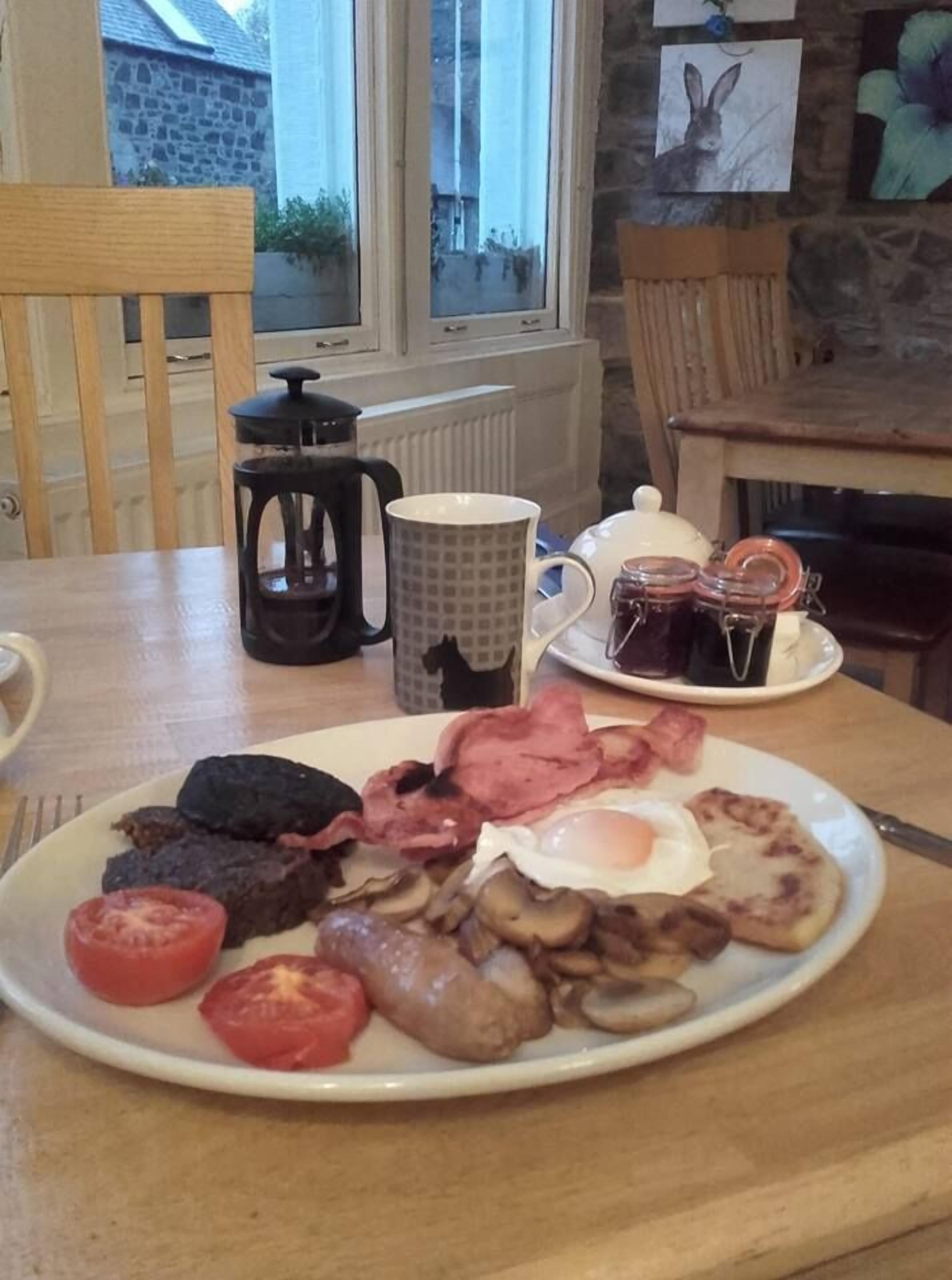 Un piatto per la colazione con uova, pancetta, funghi e pomodori.