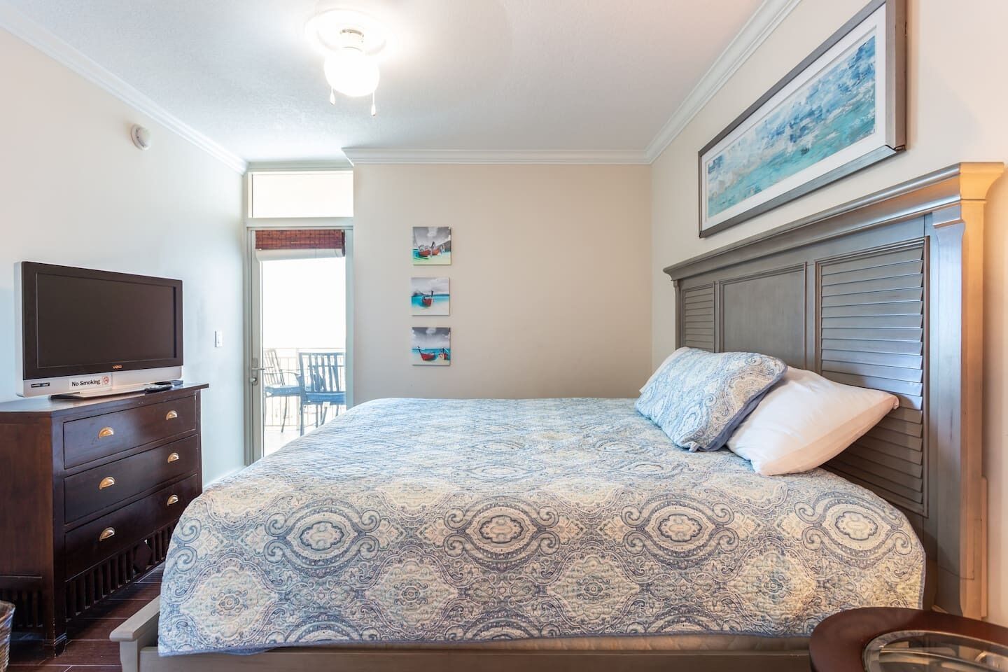 Un dormitorio con cama, cómoda, televisor y un cuadro en la pared.