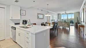 Een moderne keuken met witte kasten, een groot eiland en een eethoek met uitzicht op de stad.