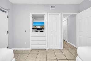 A hotel room with a white door, a television on a stand, a white cabinet, and a tiled floor. - St. Maarten 402: Elegant 3BR Beachfront Condo in Silver Shells (Destin)