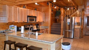 A wooden cabin-style kitchen with granite countertops, a stainless steel refrigerator, and a built-in oven. - 'Mountainscape'-Million Dollar Views In Legacy Mtn. 10% off 7 night rental! (Pigeon Forge)