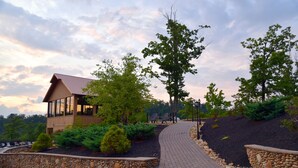A lodge with a wooden exterior, a stone retaining wall, and a paved walkway leading to the entrance. - 'Mountainscape'-Million Dollar Views In Legacy Mtn. 10% off 7 night rental! (Pigeon Forge)