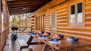 Eine Holzhütte mit überdachter Veranda, Picknicktischen und einer Hängematte.