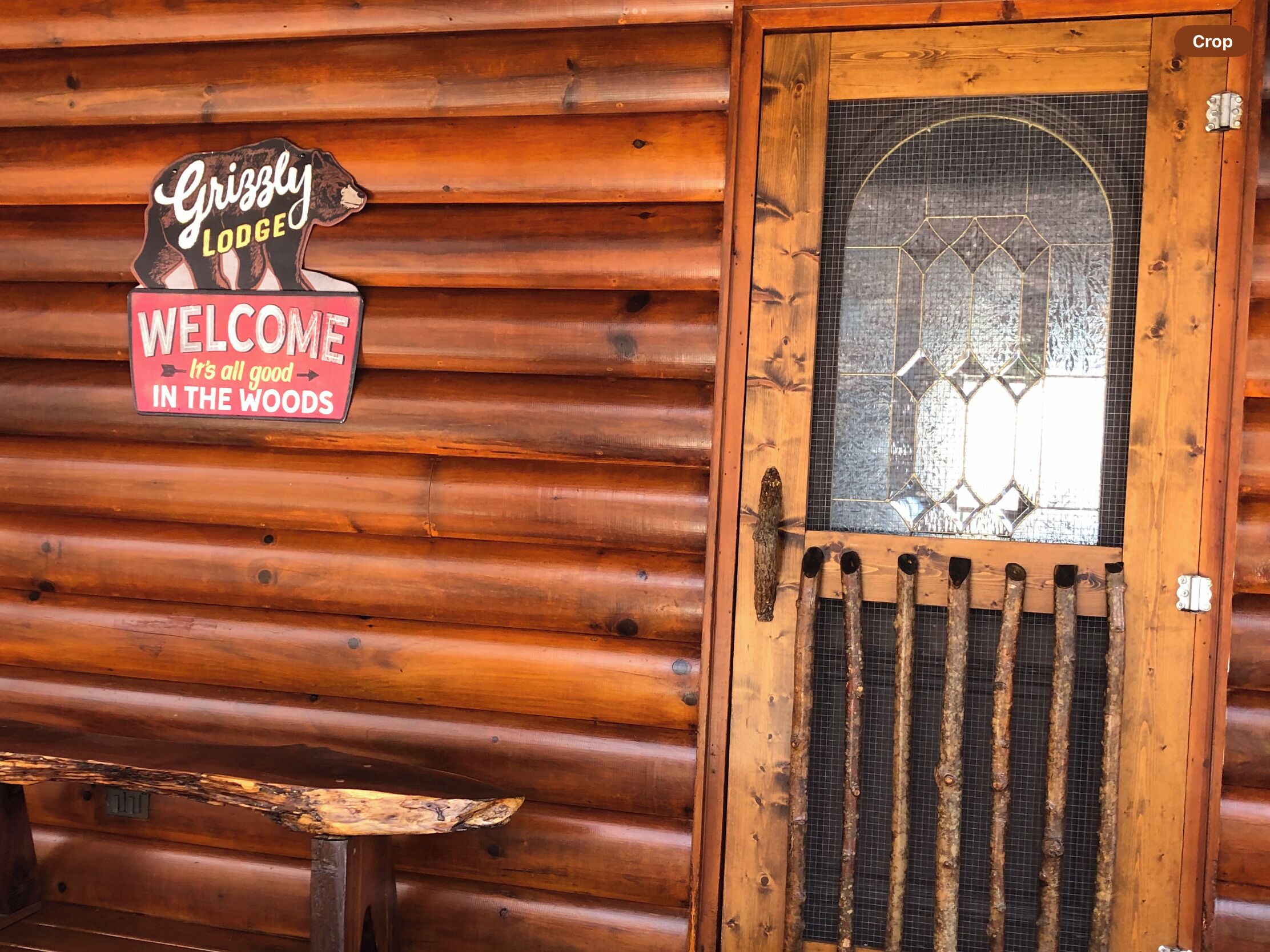 A wooden cabin with a rustic welcome sign and a glass door with a metal grill.