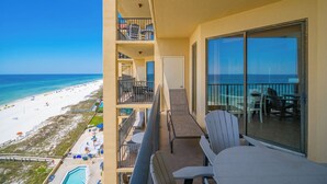 A balcony with a view of the beach and ocean, a pool, and outdoor seating. - One bedroom…Phoenix V…Gulf Front Condo #1214 (Orange Beach)