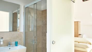 Un baño moderno con cabina de ducha de vidrio, un lavabo blanco y un espejo.