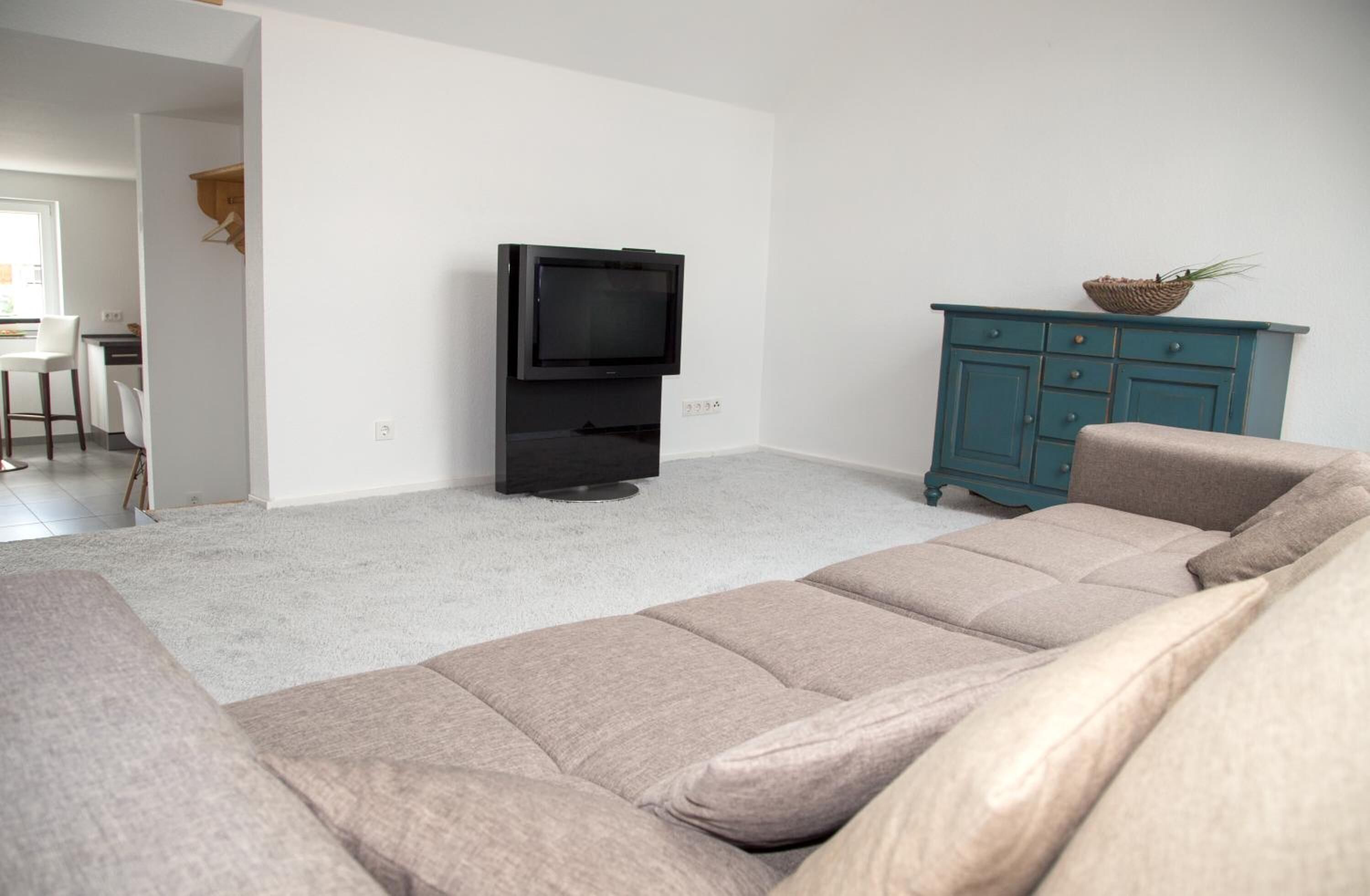 A living room with a beige sofa, a television, and a teal cabinet.