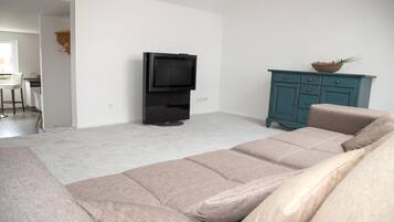 A living room with a beige sofa, a television, and a teal cabinet.