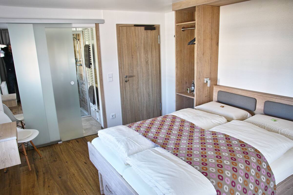 A bedroom with a bed, a wardrobe, a mirror, and a door leading to a bathroom.