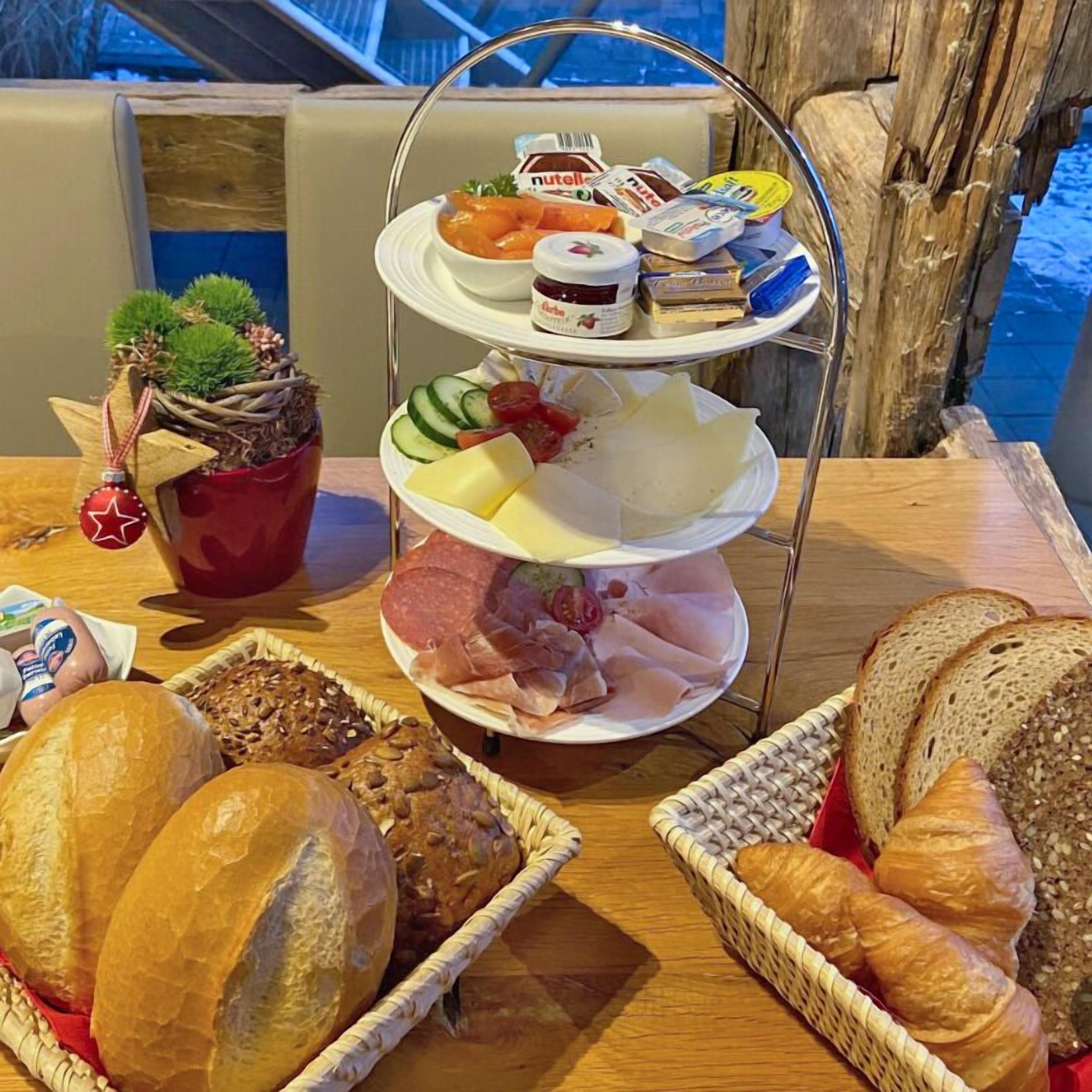 A buffet table with various food items including bread, pastries, cheese, and deli meats.