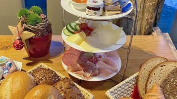 A buffet table with various food items including bread, pastries, cheese, and deli meats.