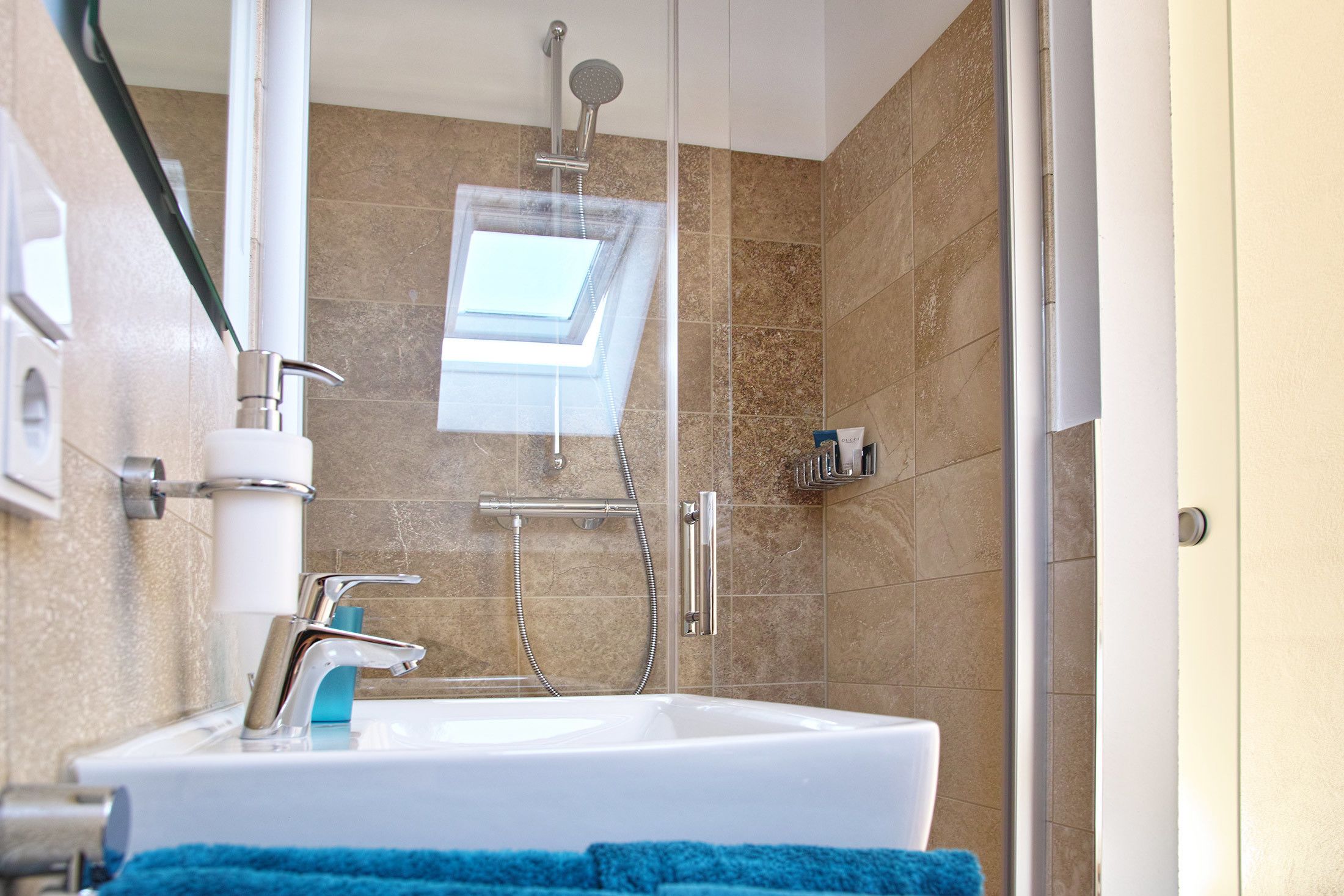 Un baño moderno con tragaluz, ducha e lavabo.