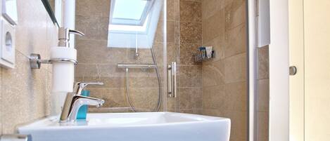 Un baño moderno con tragaluz, ducha e lavabo.
