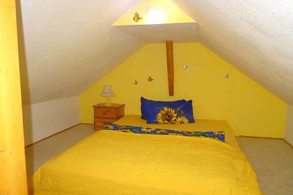 A small, yellow-themed bedroom with a single bed, a nightstand, and a lamp.