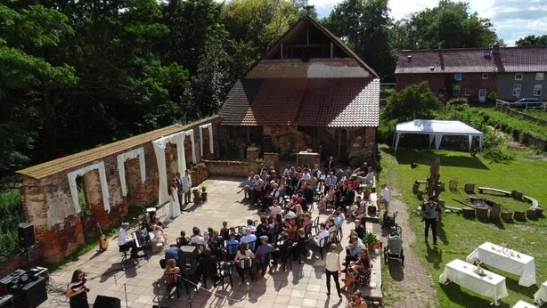 An outdoor event with a stage, seated audience, and tables set up for dining. - Elbschloss Kehnert (Tangerhütte)