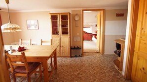 A dining area with a wooden table and chairs, a cabinet with glass doors, a clock on the wall, and a door leading to another room. - Elbschloss Kehnert (Tangerhütte)