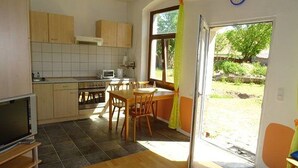 A compact kitchen with a dining area, a TV, and a window with curtains. - Elbschloss Kehnert (Tangerhütte)