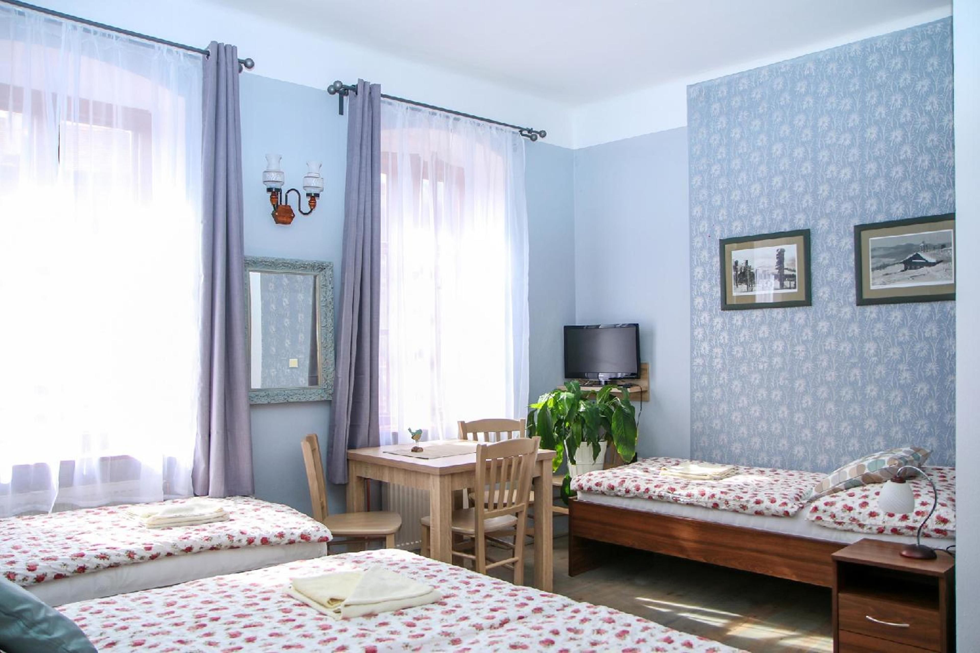 Una habitación con dos camas, un escritorio, una silla, un televisor y una planta.