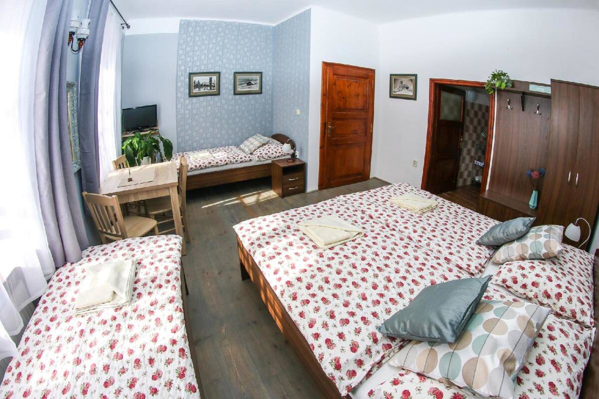 A bedroom with two beds, a desk, a chair, and a wardrobe.