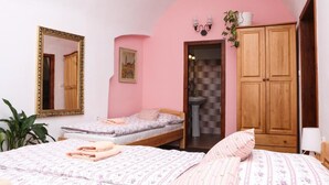 A bedroom with two beds, a mirror, a wardrobe, and a bathroom visible through an archway. - Mini Hotel Abraka (Cesky Krumlov)