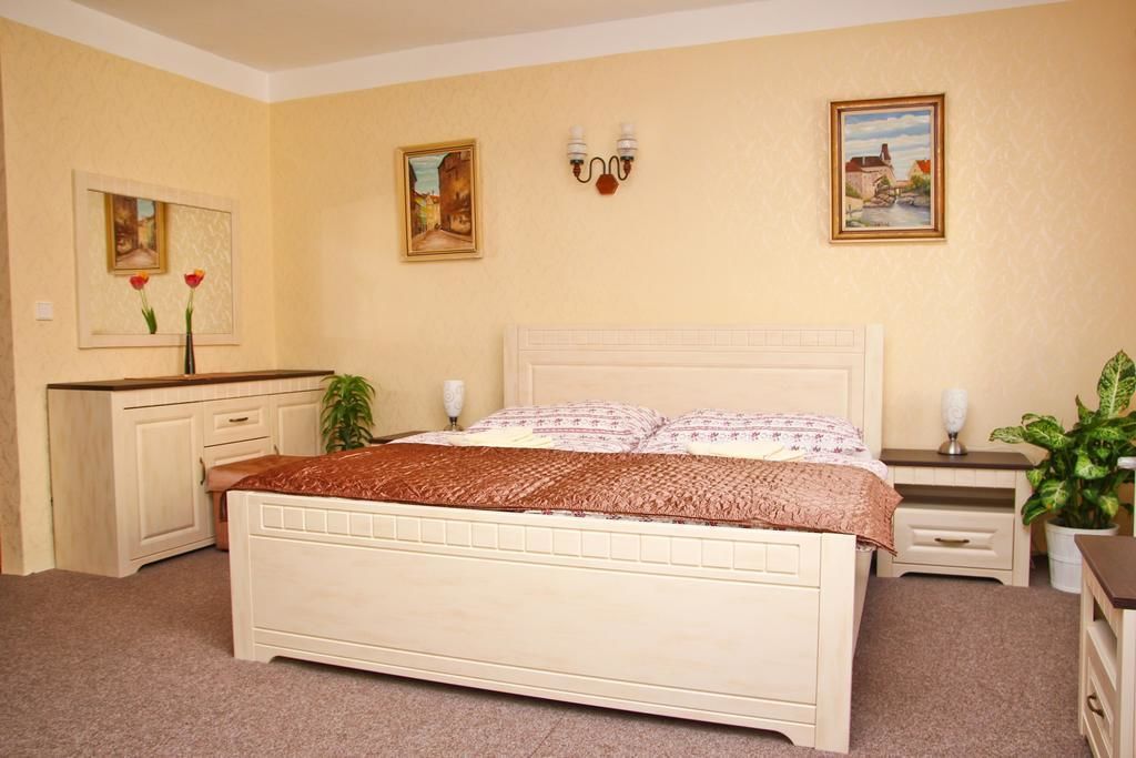 Un dormitorio con una cama grande, un aparador, una mesita de noche y dos lámparas de pared.