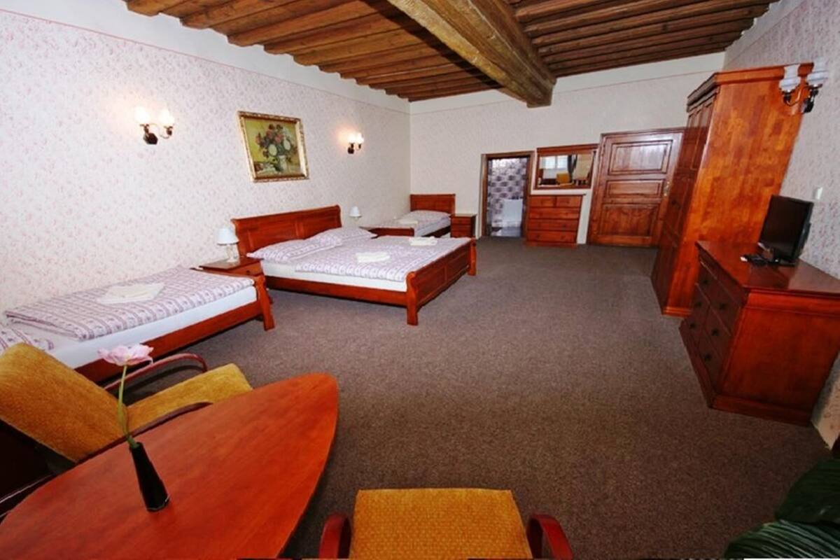 A hotel room with two single beds, a wooden desk, a chair, a TV, and a wardrobe.
