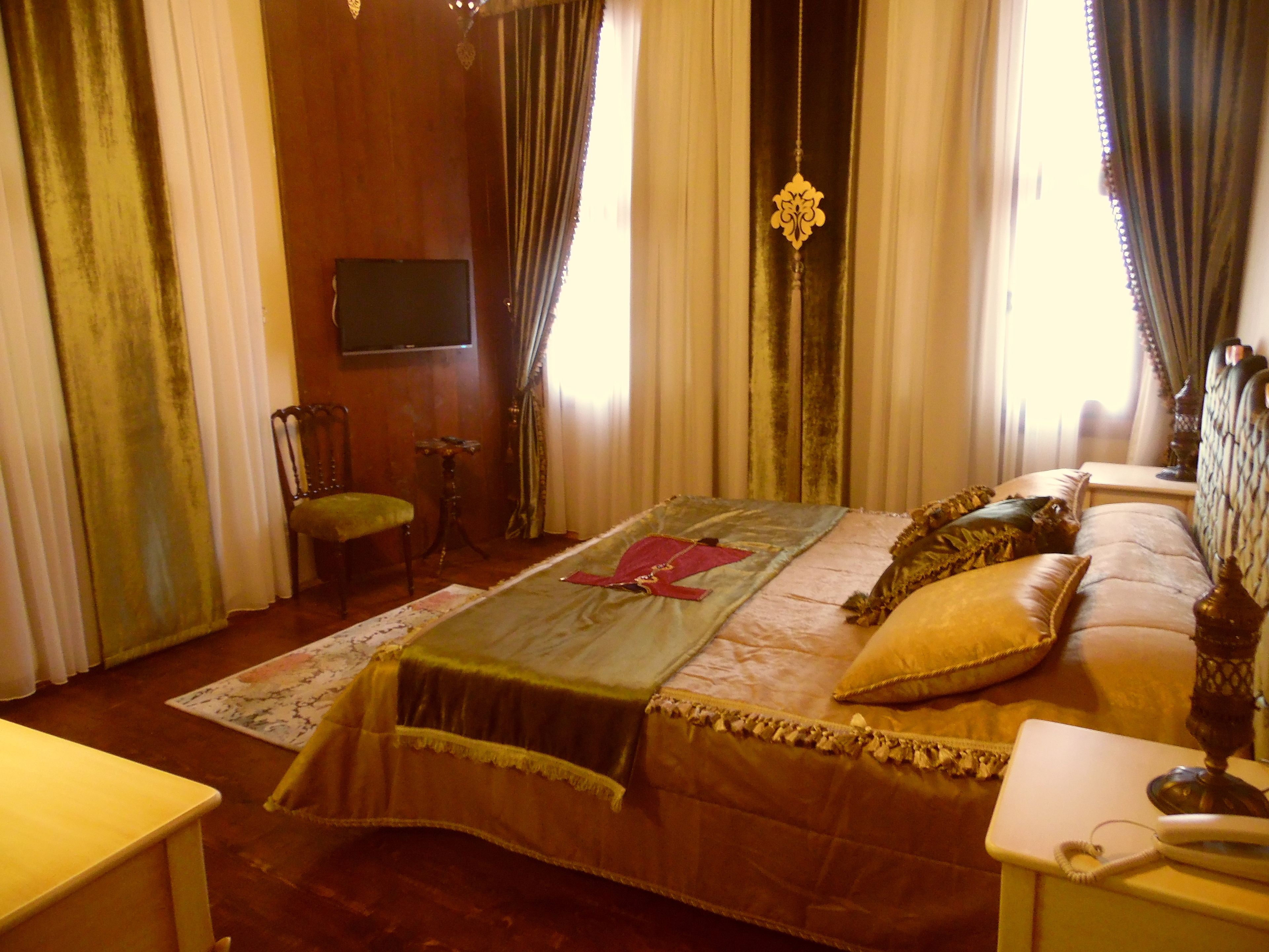 A room with a bed, a chair, a small table, and curtains.