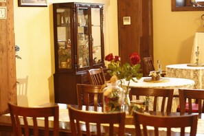 Enjoy a family meal or quiet dinner in this warm dining area with a round table for four, a vase with flowers, and a cabinet for displaying decorative items.