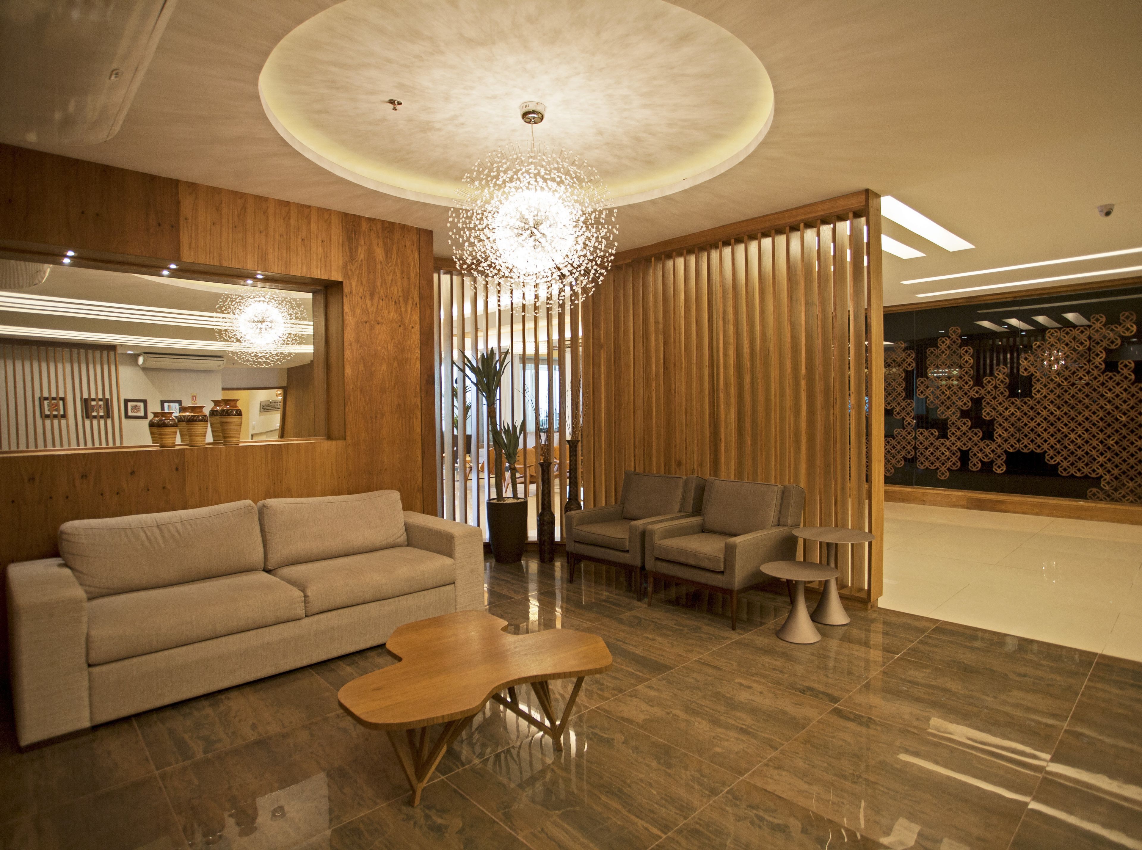 A modern interior with a sofa, chairs, a wooden coffee table, and a decorative light fixture.