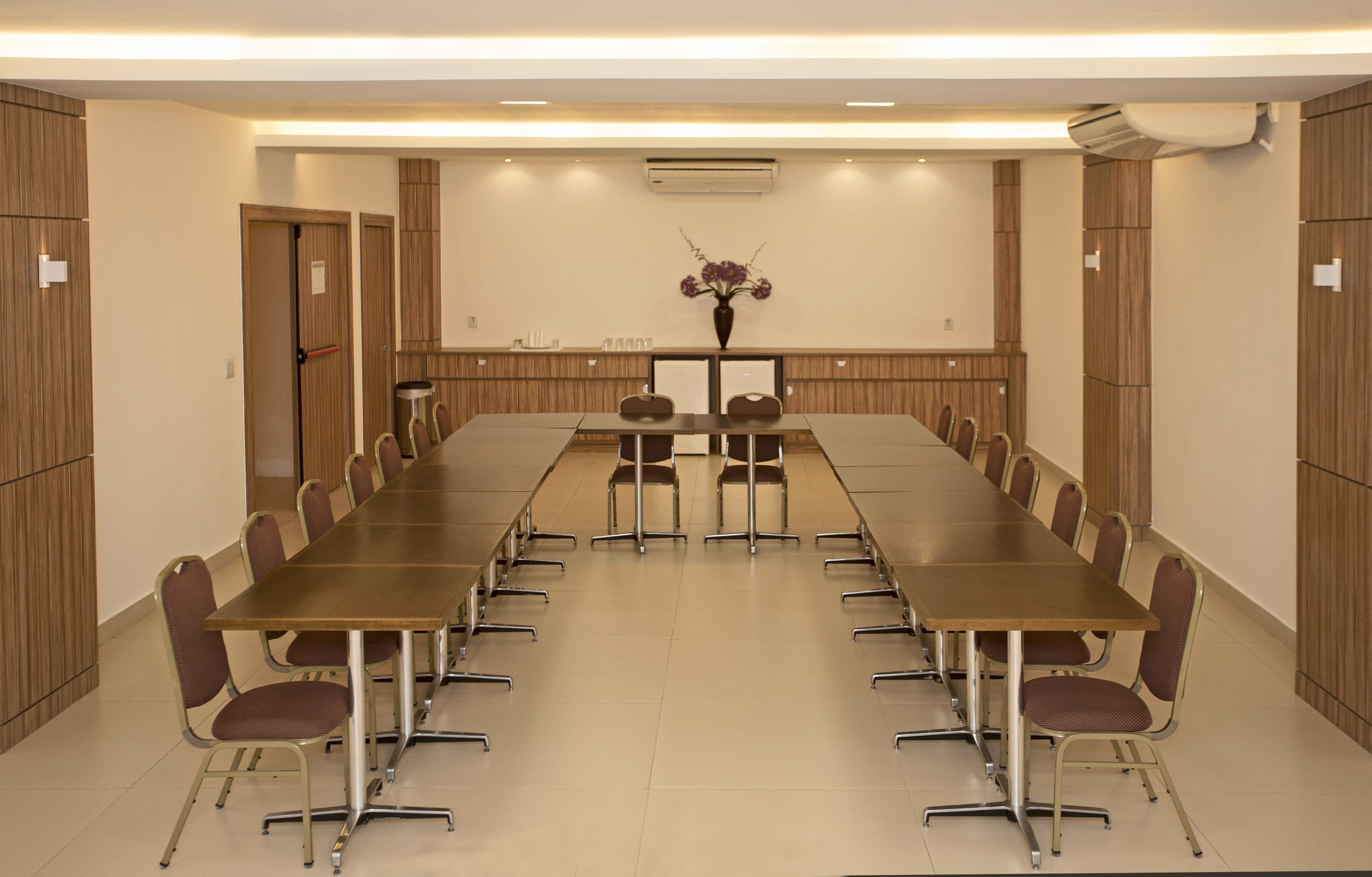 A conference room with a long table, chairs, and a vase with flowers.