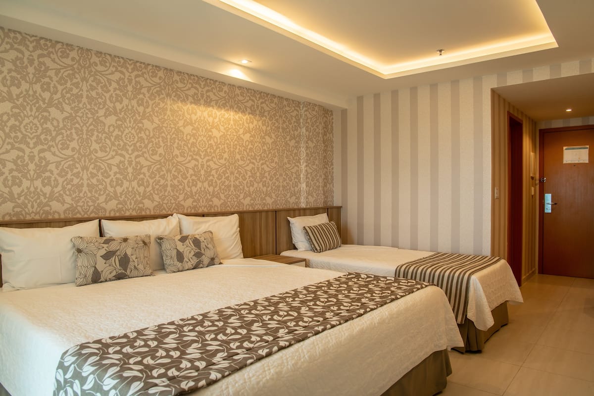 Ein Hotelzimmer mit zwei Betten, einem gemusterten Kopfteil und einer gestreiften Wand.