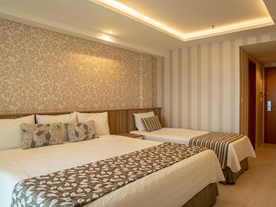 A hotel room with two beds, a patterned headboard, and a striped wall.