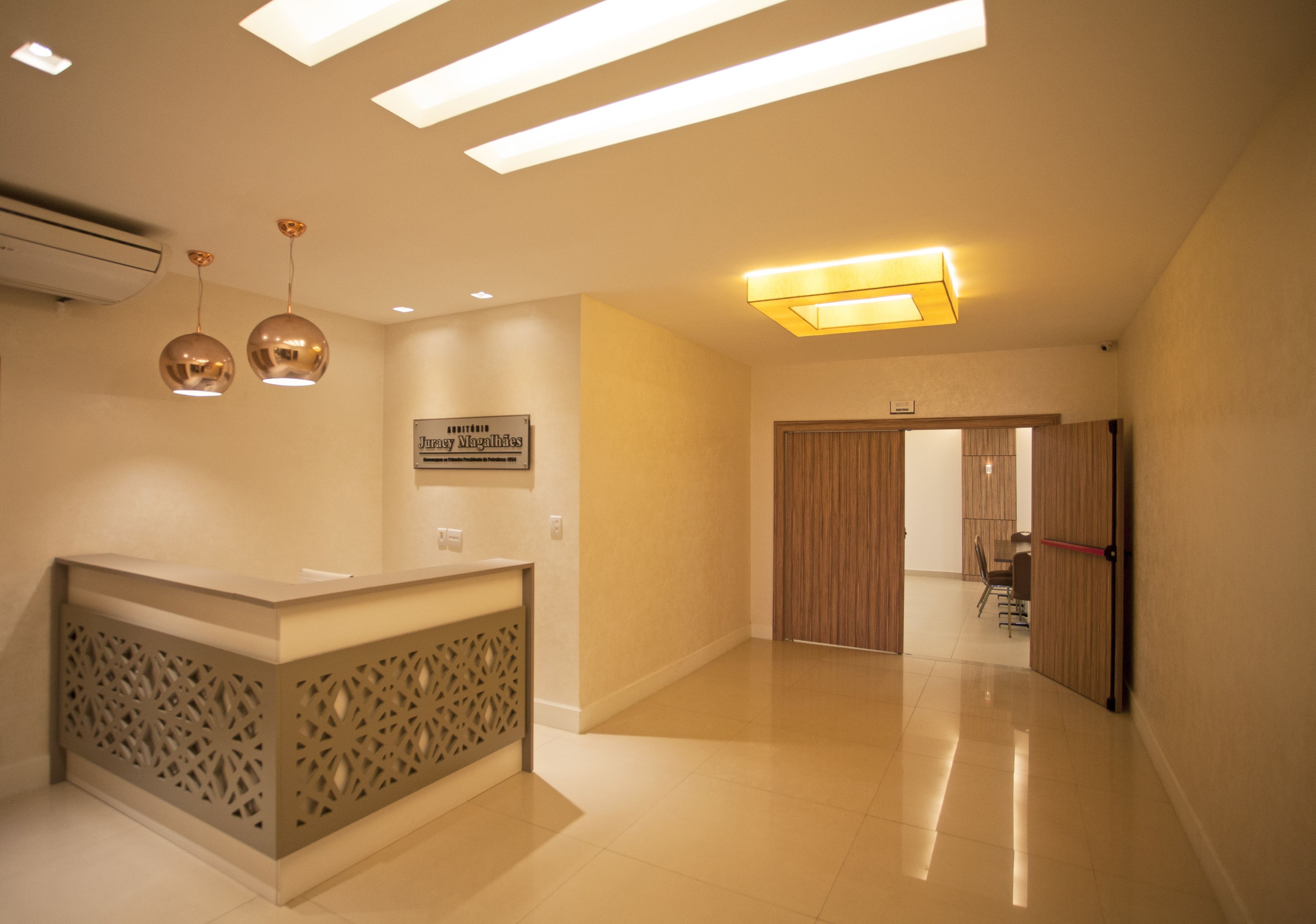 A hotel reception area with a reception desk, a sign above it, and a wooden door in the background.