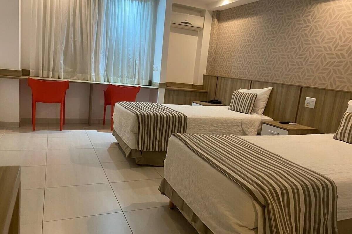 Ein Hotelzimmer mit zwei Betten, einem Schreibtisch, einem Stuhl und einer Wand mit Muster.