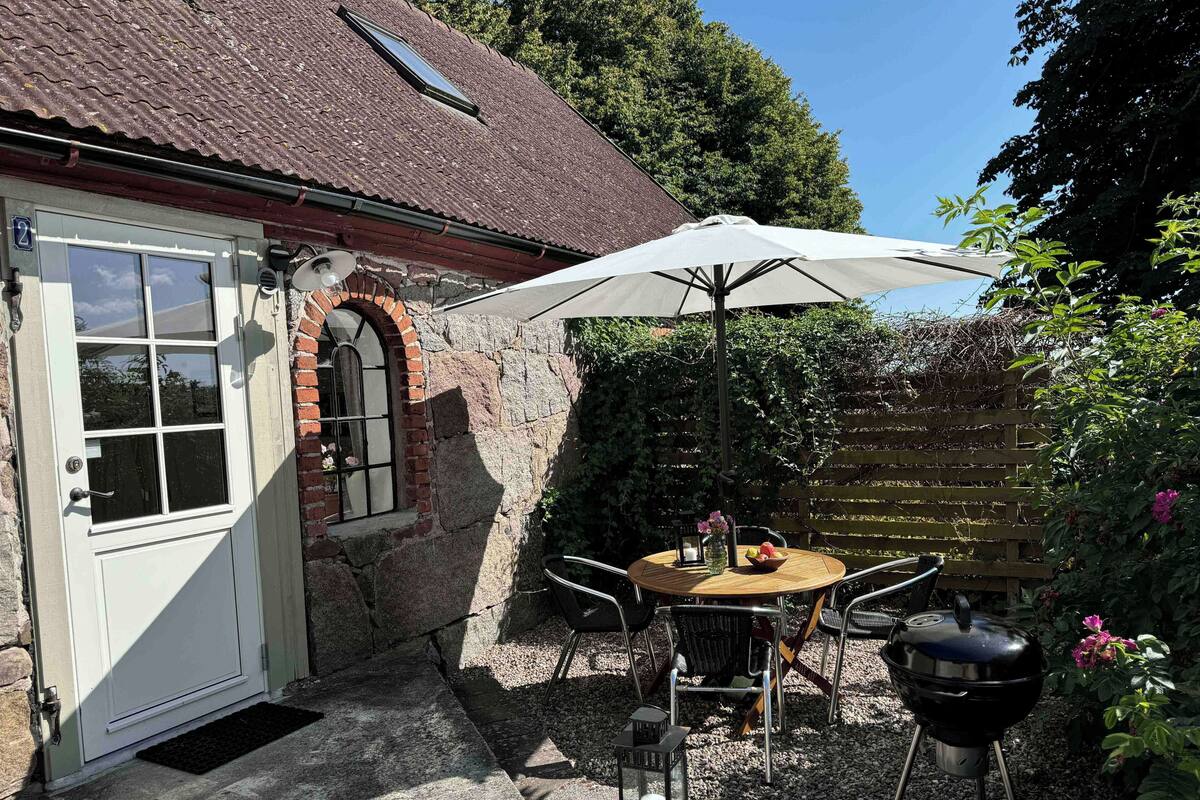 En rustik bygning i sten med en hvid dør og en muråbning.