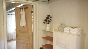 A bathroom with a wooden door, a white sink, a vase with flowers, and a towel rack. - Stenrosgården logi (Kivik)