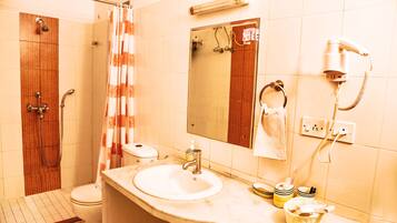 Un baño con ducha, inodoro, lavabo y un secador de pelo en la pared.