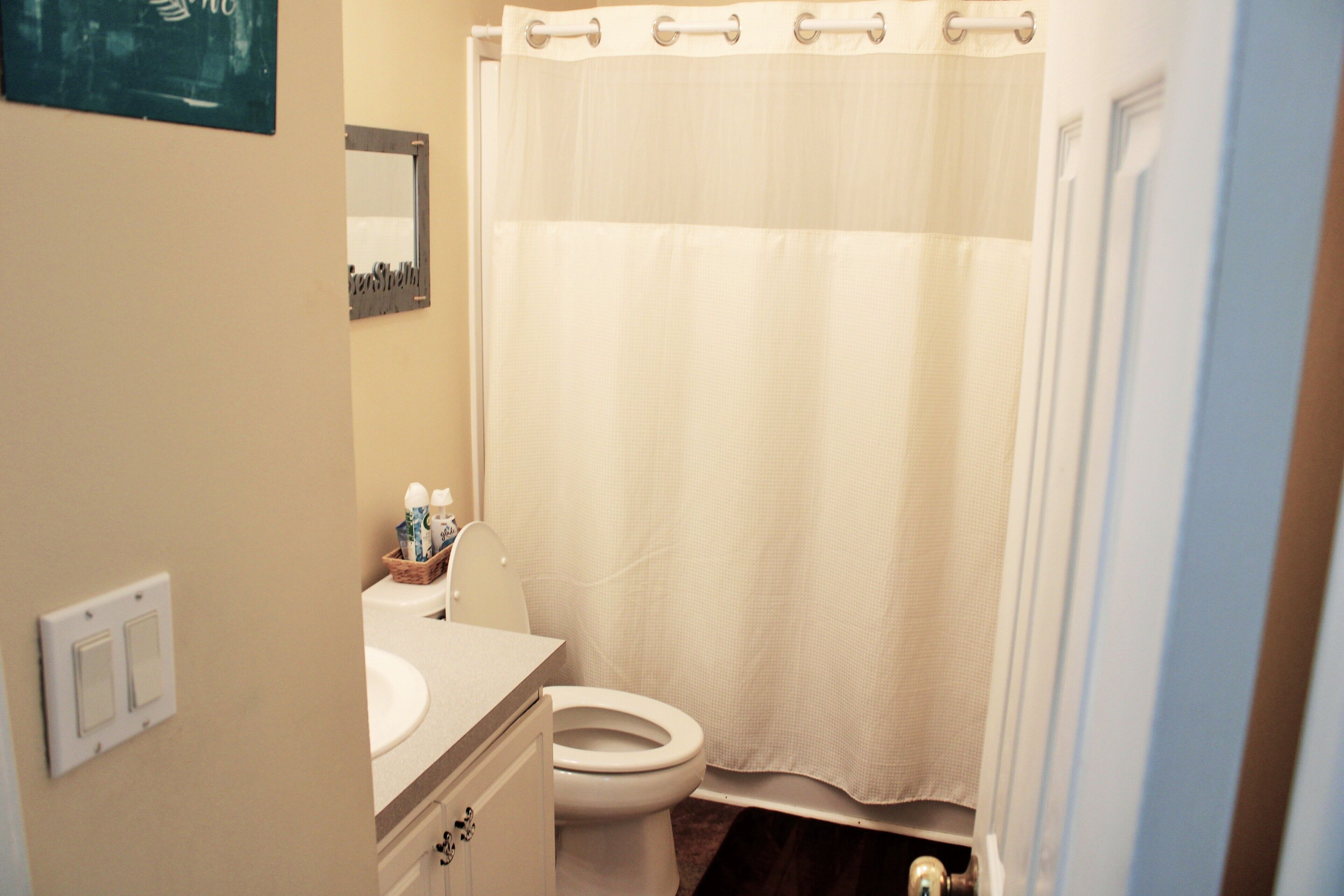 A bathroom with a toilet, sink, and a shower curtain.