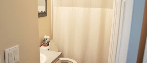 A bathroom with a toilet, sink, and a shower curtain.