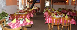 A restaurant with tables covered in red and white checkered tablecloths, wooden chairs, and yellow napkins. - Gasthof Zahn (Seegebiet Mansfelder Land)