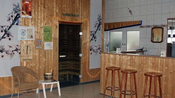 A wooden interior with a sauna, bar area, and seating.