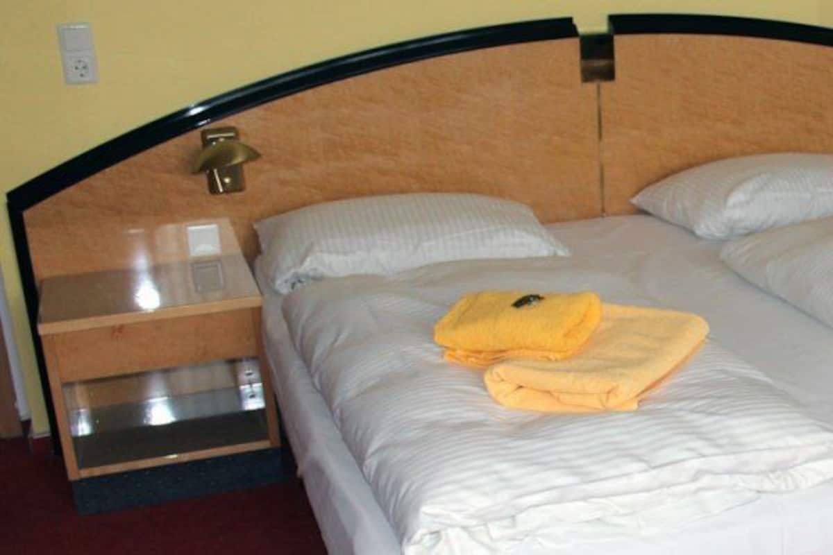 Ein Doppelbett mit zwei Nachttischen, jeder Tisch ausgestattet mit einer Lampe und einer kleinen Ablagefläche.
