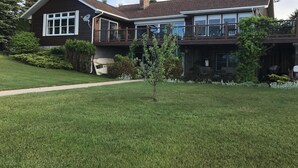 Una casa a due piani con un balcone, un garage e un prato curato.