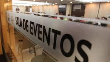 Letrero que dice "SALA DE EVENTOS" en una sala de conferencias con filas de mesas y sillas.
