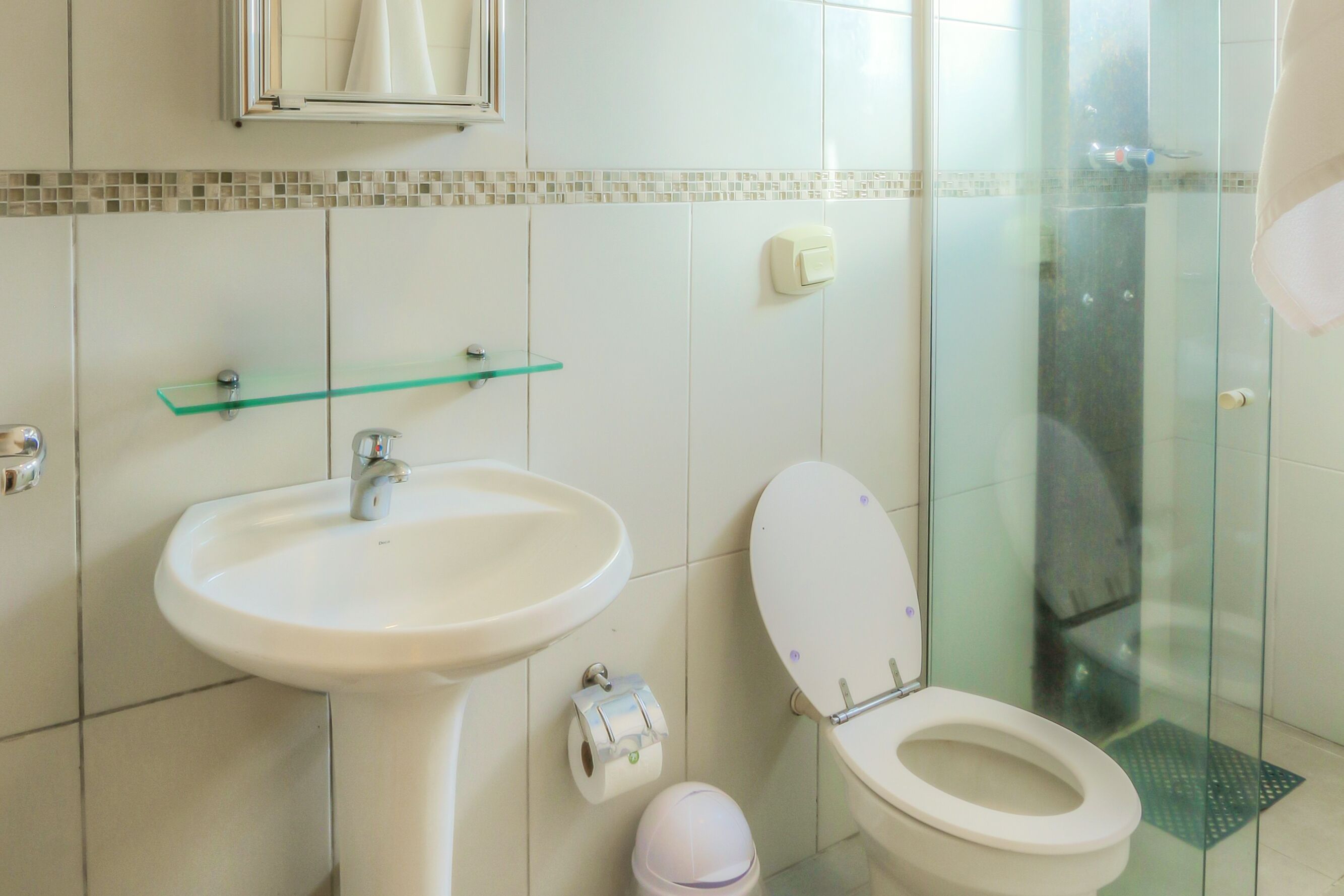 Une salle de bain avec un lavabo blanc, des toilettes et une cabine de douche en verre.