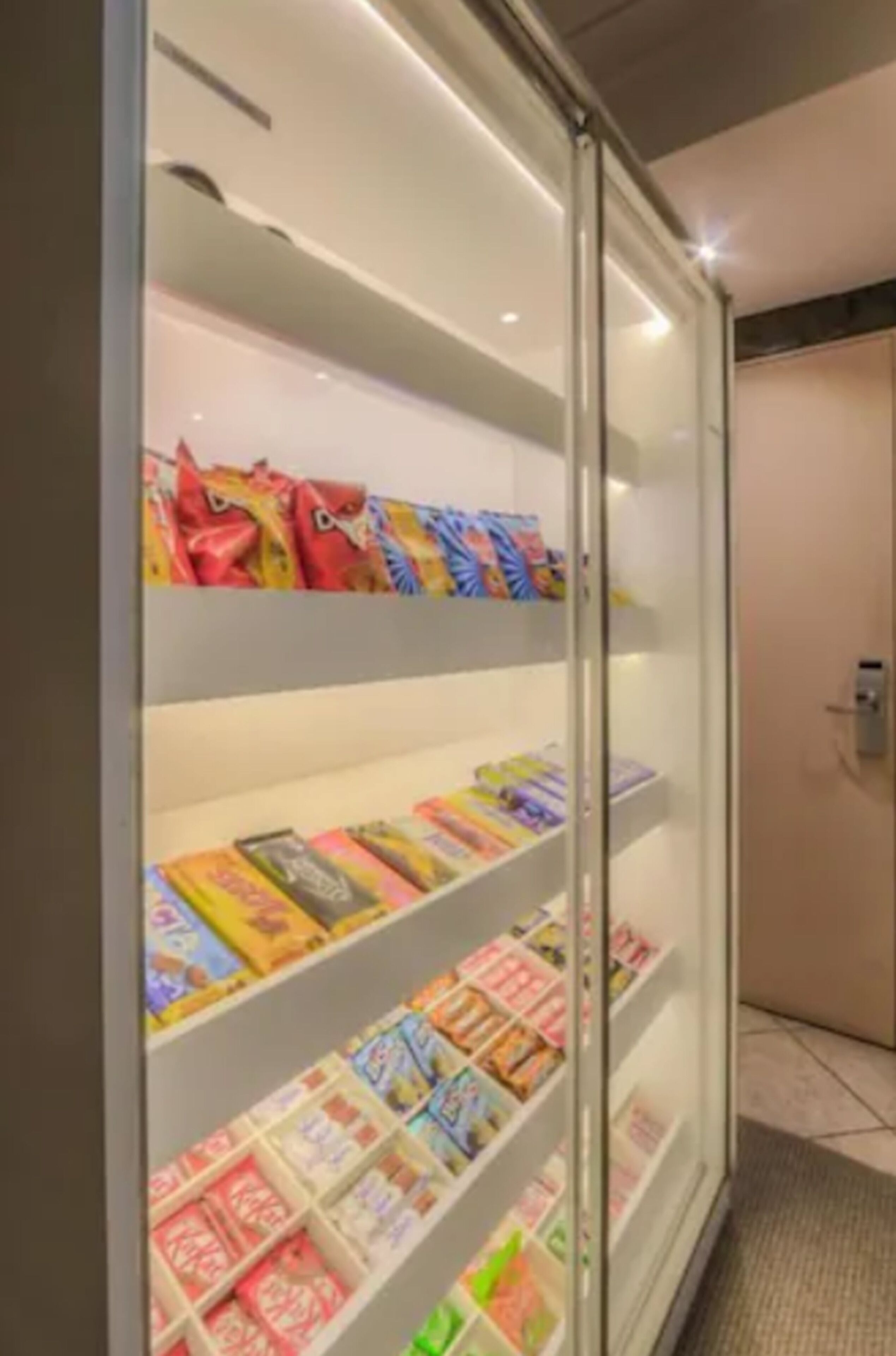 Una vitrina de vidrio con diversos artículos coloridos, posiblemente aperitivos o pequeños productos, dispuestos en estantes.