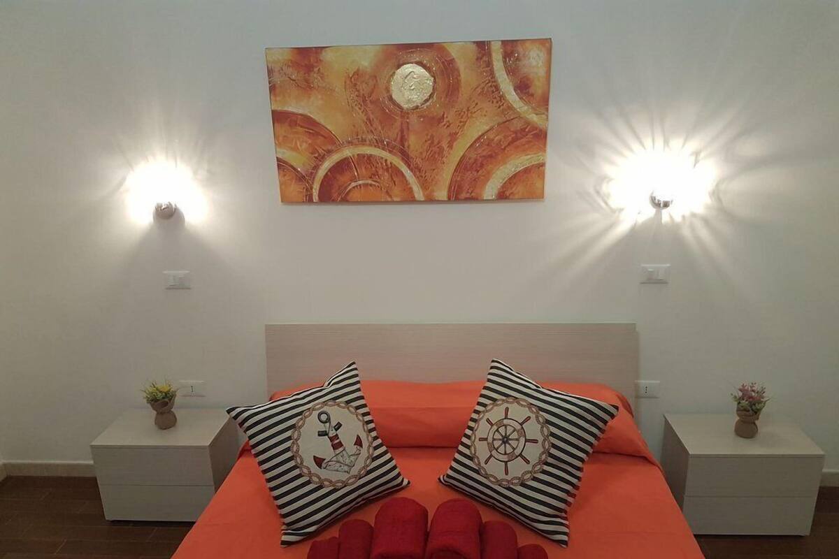 Een hotelkamer met een bed, twee nachtkastjes, een wandlamp en een schilderij.