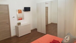 Une chambre à coucher comprenant un lit, une commode, un téléviseur et une armoire.