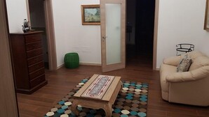 Un salon avec une table basse en bois, un pouf vert, un canapé beige et un tapis à motifs.