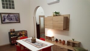 Un coin repas avec une table blanche, des chaises rouges et un buffet en bois au-dessus.